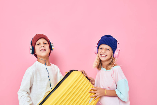 vreugdevolle jongen en meisje voor te bereiden op de feestdagen jonge reizigers roze kleur achtergrond - Foto, afbeelding