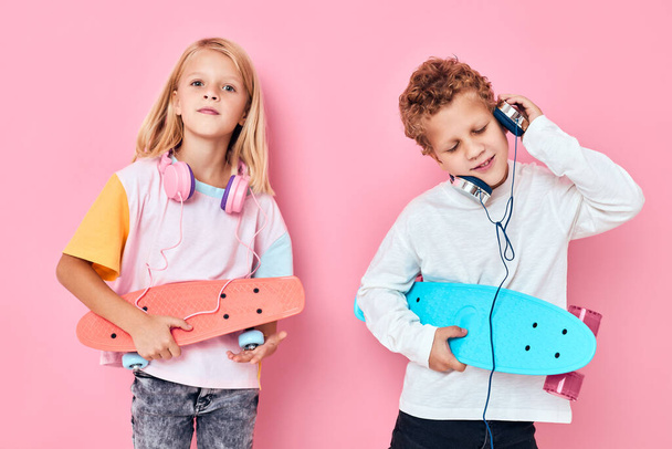 leuke kinderen hoofdtelefoon mode skateboards roze achtergrond - Foto, afbeelding