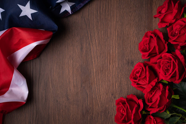 Concept of U.S. Independence day or Memorial day. National flag and red rose over dark wooden table background. - Фото, зображення