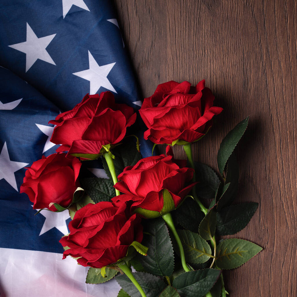 Concept of U.S. Independence day or Memorial day. National flag and red rose over dark wooden table background. - Foto, imagen