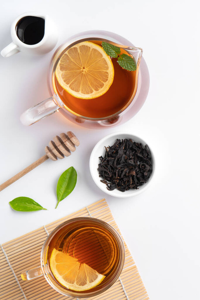 Design concept top view of honey black tea with yellow lemon and mint leaf on white table background. - Fotó, kép