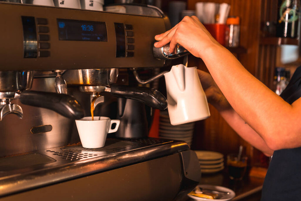 A waitress at a coffee machine putting a decaf into a white cup - Foto, immagini