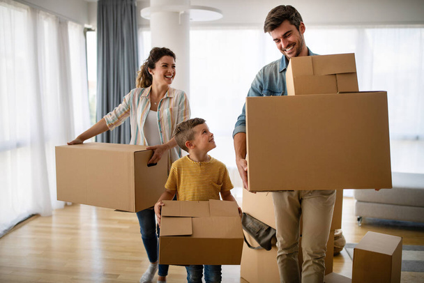 Happy family unpacking boxes in new home on moving day. People, real estate, new home concept - Photo, Image