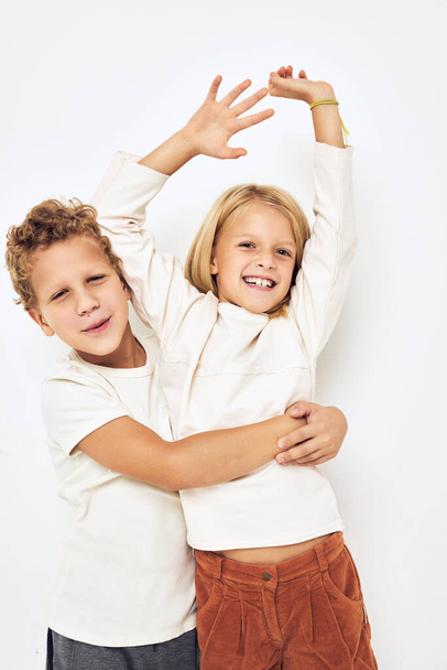 Два дошкольных ребенка мальчик и девочка обнимают весело детство изолированный фон - Фото, изображение