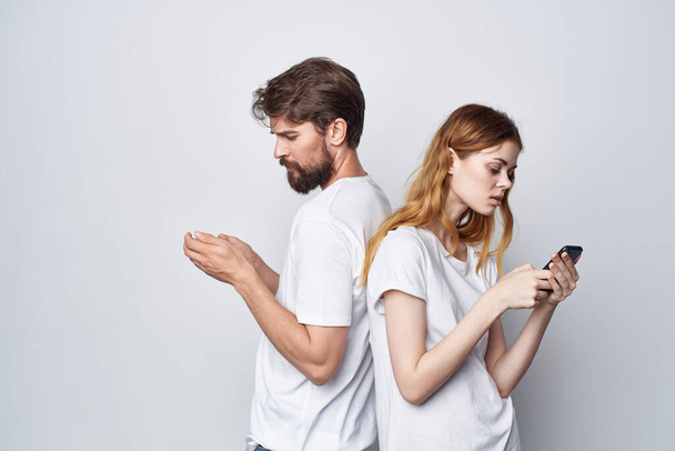 a young couple in white T-shirts with phones in their hands studio lifestyle - 写真・画像