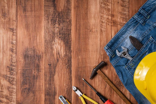 Top view design concept of Labor Day with working tools and jeans on wooden table background. - Fotó, kép