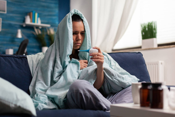 Blanke vrouw meten temperatuur ziek thuis - Foto, afbeelding