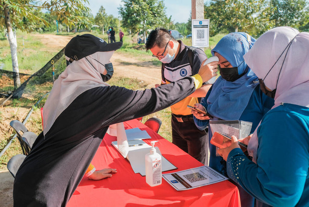Muadzam Shah, Malaysia - October 6th, 2021 : Asian women getting her temperature taken with an infrared thermometer  at durian and pineapple orchards in Muadzam Shah - Φωτογραφία, εικόνα