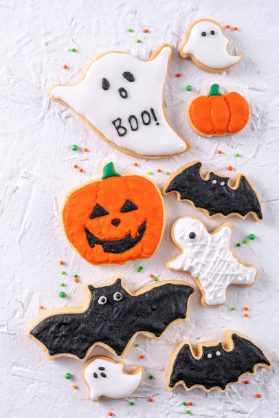 Top view of Halloween festive decorated icing gingerbread sugar cookies on white background with copy space and flat lay layout. - 写真・画像