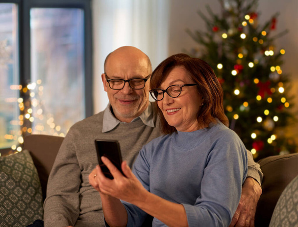 happy senior couple with smartphone on christmas - 写真・画像