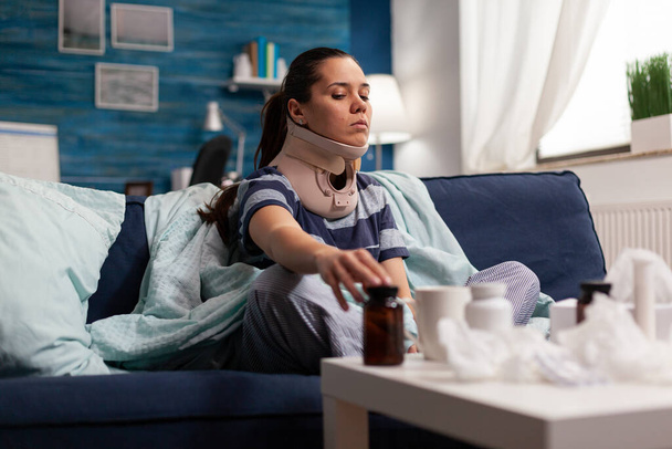 Γυναίκα με κολάρο στον λαιμό που υποφέρει από πόνο στον καναπέ - Φωτογραφία, εικόνα