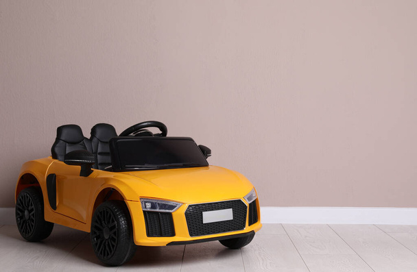 Child's electric toy car near beige wall indoors. Space for text - Photo, Image