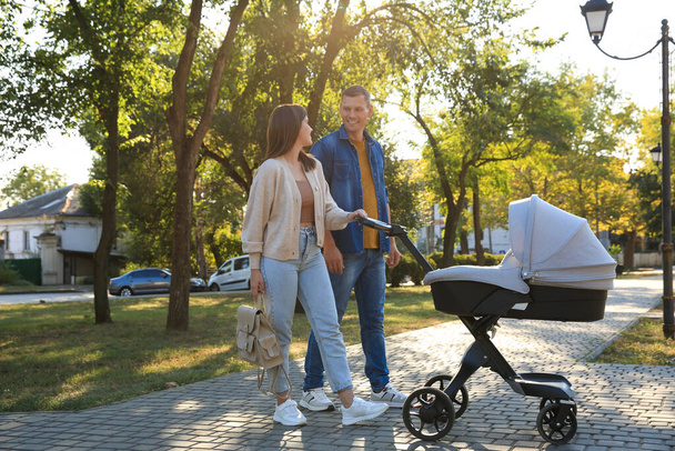 Happy parents walking with their baby in stroller at park on sunny day - Foto, Bild