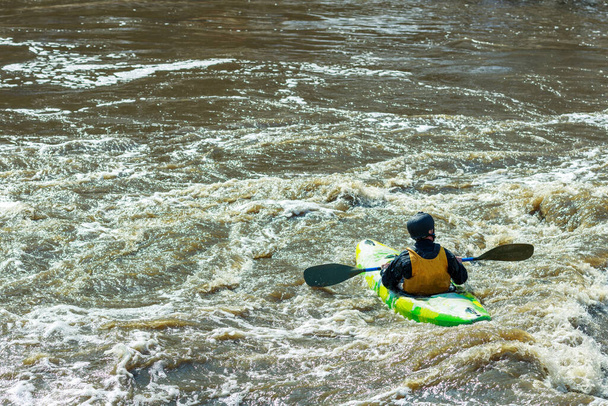 un hombre flotando en el río en un kayak. El agua tormentosa está sucia alrededor del barco. recreación activa en el río - Foto, imagen