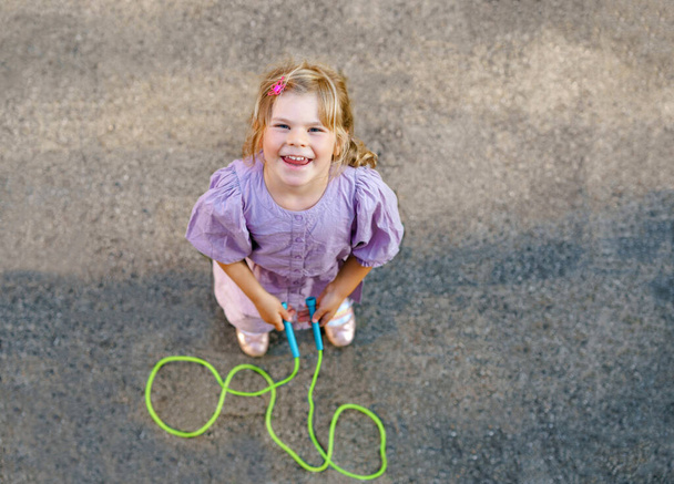 Little preschool girl jump and train with skipping rope. View from above on cute happy active child. Summer sports and activity for physical and mentally fitness of children. - Photo, Image