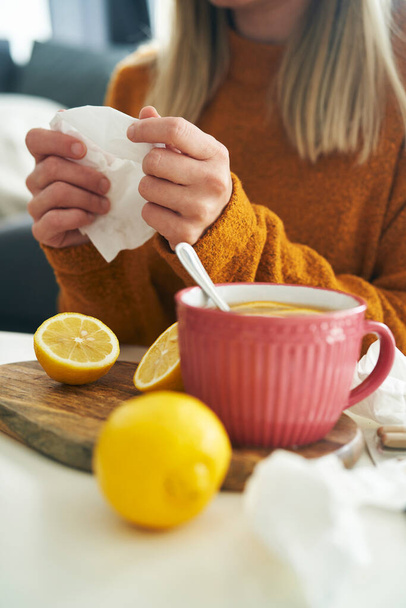 Vertical image of ill woman with tissue and hot tea - Foto, immagini
