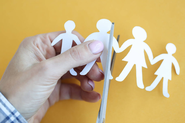 Woman hand cuts paper figures in form of family with scissors closeup - Photo, Image