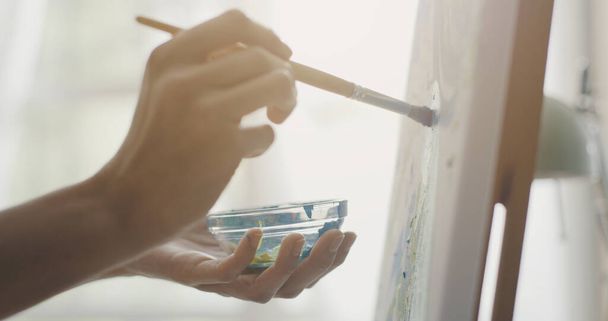 Creative artist painting on canvas with a paintbrush, inspiration and hobby concept - 写真・画像