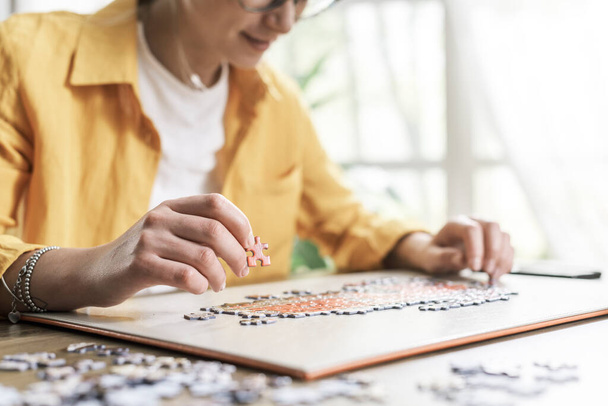 Woman sitting at desk at home and solving a puzzle, leisure and games concept - Foto, Bild