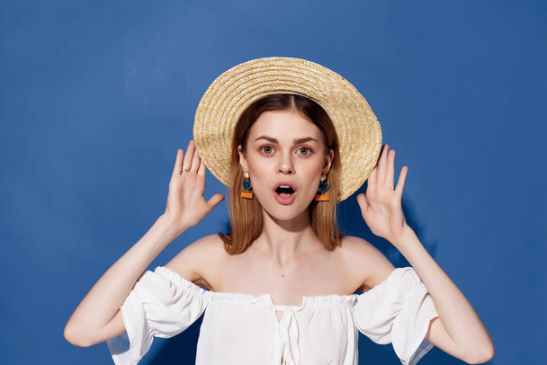 atraktivní žena v klobouku pózující na modrém pozadí. Kvalitní fotografie - Fotografie, Obrázek