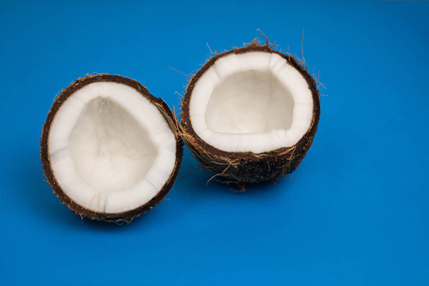 halves of fresh coconut on a blue background - 写真・画像