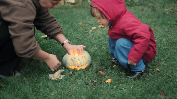 Mom and a cute little girl are lighting candles inside a pumpkin for Halloween - Footage, Video
