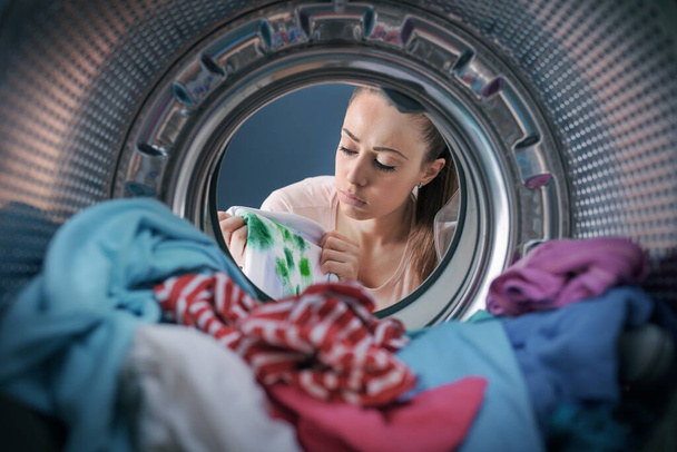 Disappointed woman finds stained clothes in the washing machine after doing laundry, point of view shot - Photo, Image
