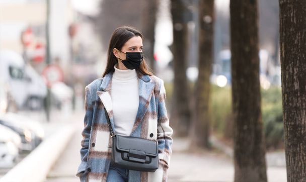 Young woman wearing a protective face mask and walking down the street - Foto, immagini