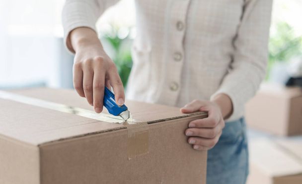 Woman opening a box using a cutter, hands close up - Foto, afbeelding