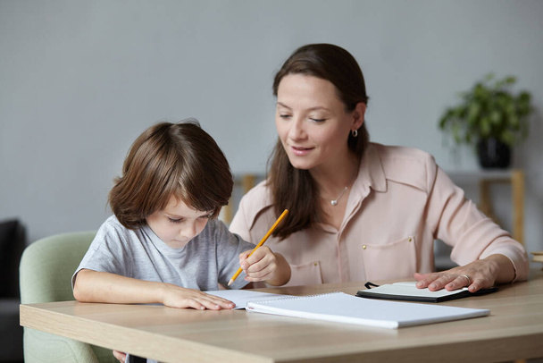 Otthonról tanítani egy kedves kisfiút írni és festeni. Egy fiatal, gyönyörű anya oktató. - Fotó, kép