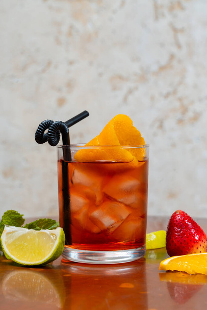 Склянка бульварного коктейлю з кубиками льоду та апельсиновою цедрою з фруктами навколо
 - Фото, зображення