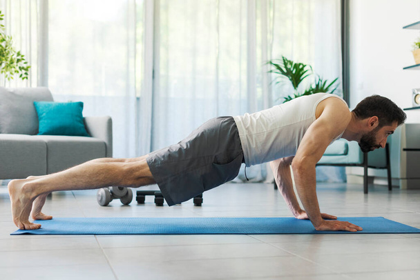 Man doing push ups at home, he is exercising on the floor - Valokuva, kuva