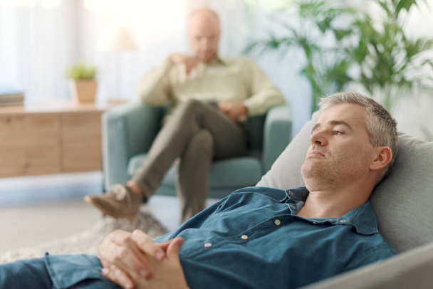 Patient lying on the couch during a therapy session with his psychologist - Zdjęcie, obraz