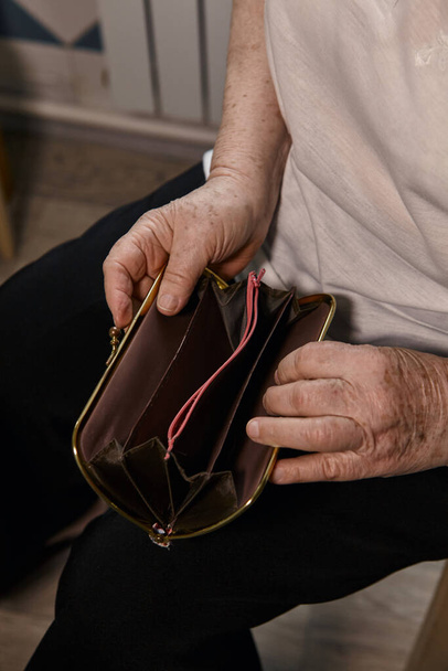 The older woman counts the money. An elderly woman Caucasian old woman gray-haired grandmother takes money out of her purse and counts it. Old hands hold bills.  - Foto, Bild
