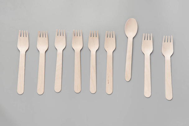Wooden spoon, fork, paper cups gray background. Disposable tableware made of natural materials. The concept of a zero waste, sustainable lifestyle. Eco-friendly disposable tableware - Photo, Image