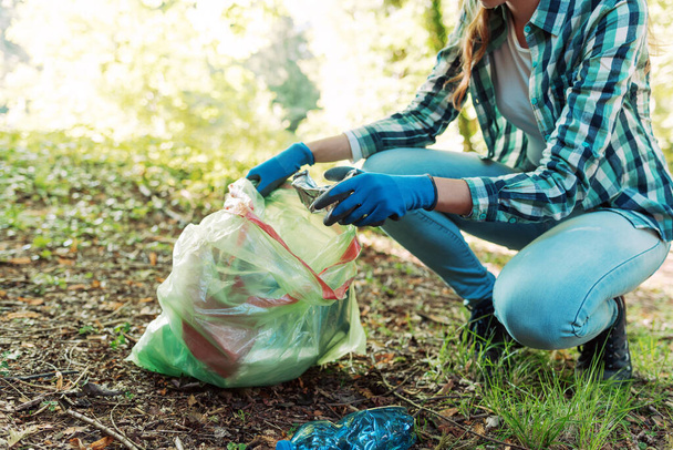 Cleanup volunteer collecting trash in the forest and holding a garbage bag, environmental protection concept - 写真・画像