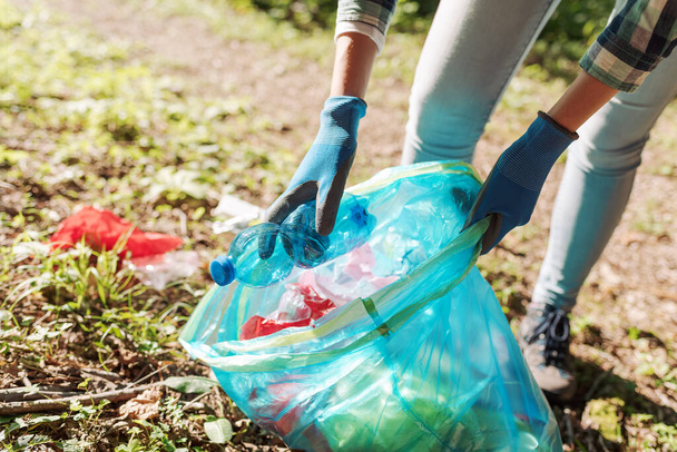 Cleanup volunteer collecting trash in the forest and holding a garbage bag, environmental protection concept - Foto, immagini