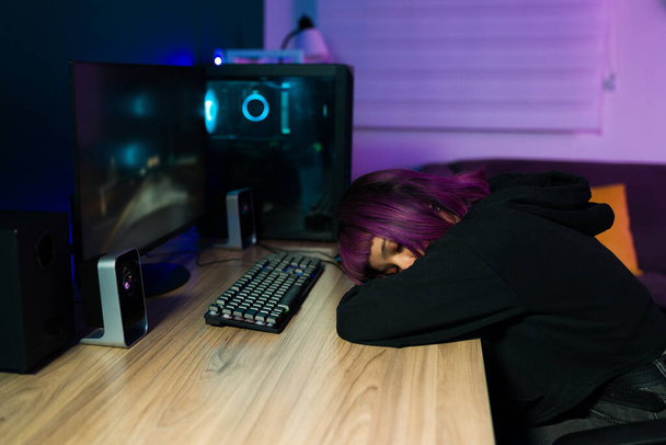 Fatiguée jeune femme avec casque mettre sa tête sur le bureau et dormir après avoir joué à des jeux vidéo en ligne - Photo, image