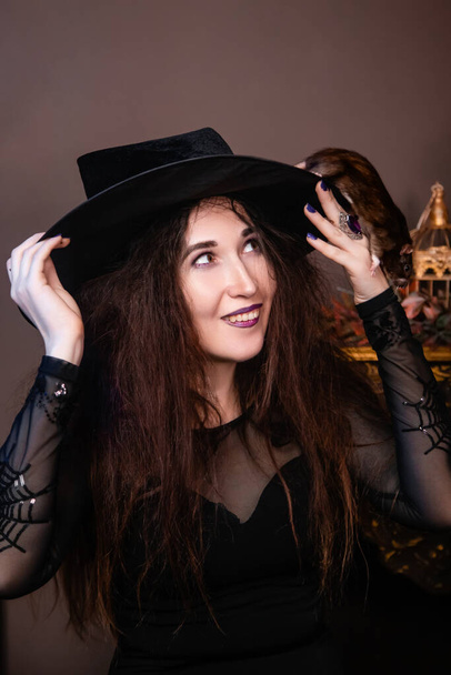 Portrait of a witch in black clothes with disheveled hair with a rat in her hands. Halloween celebration concept. - Foto, Imagem