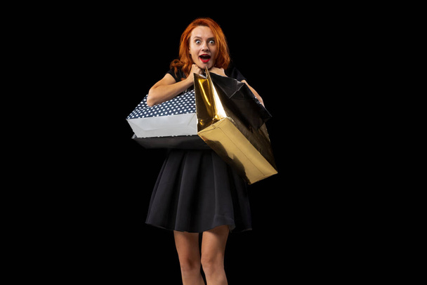 Portrait of happy and excited woman holding many bags after successful shopping isolated over black background. Sales - Foto, Bild