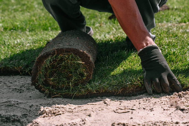Empilhamento profissional de grama laminada fresca. Mãos de jardineiro em luvas de jardinagem que colocam relva fazendo novo gramado - Foto, Imagem