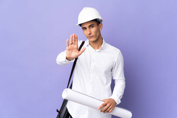 Young architect man isolated on background making stop gesture - Photo, Image