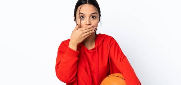 Mladá žena hraje basketbal přes izolované bílé pozadí pokrývající ústa s rukama - Fotografie, Obrázek
