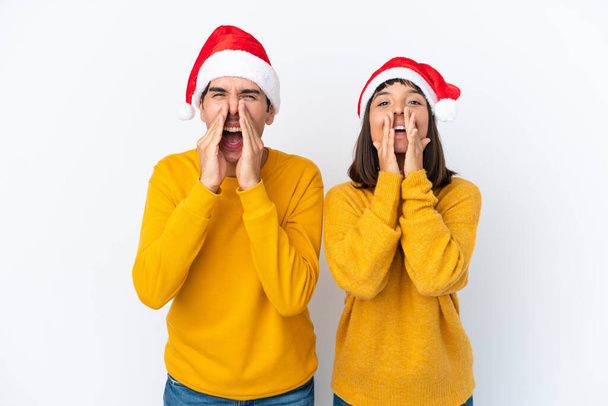 Молодая смешанная раса пара празднует Рождество изолированы на белом фоне кричать и объявлять что-то - Фото, изображение