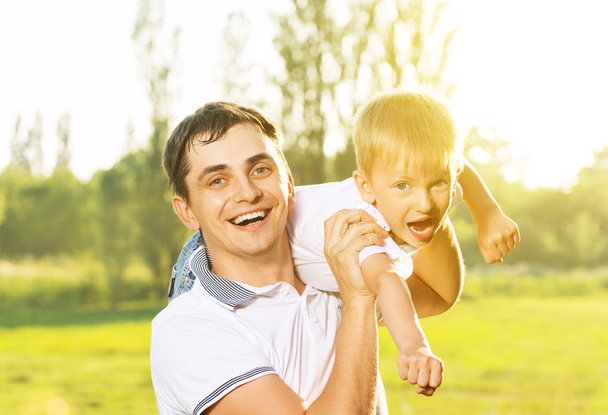 feliz papá e hijo abrazando, jugando y riendo en la naturaleza de verano
 - Foto, Imagen