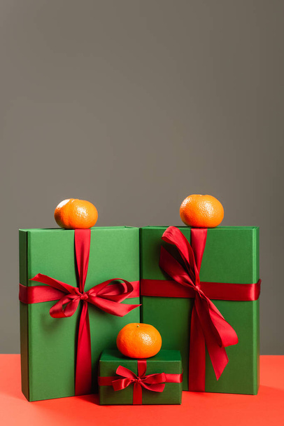 mandarinas sobre regalos envueltos en verde aislados en gris  - Foto, imagen