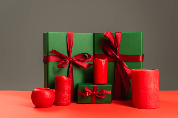 red candles near green wrapped presents isolated on grey  - Fotoğraf, Görsel