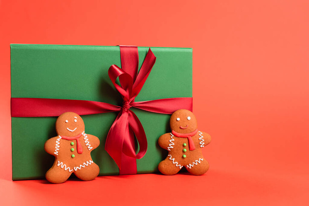 gingerbread cookies near green wrapped present on red - 写真・画像
