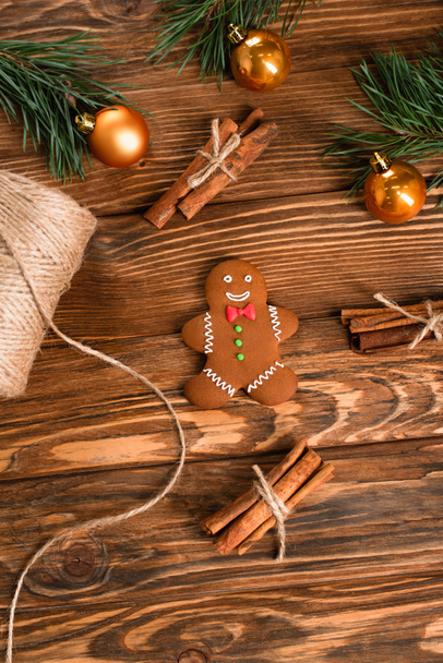 top view of gingerbread cookie, cinnamon sticks and fir branches on wooden surface - Photo, Image