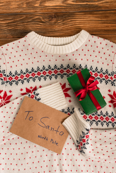 pohled shora na dopis Santovi v blízkosti dárkové krabičky na pleteném svetru  - Fotografie, Obrázek